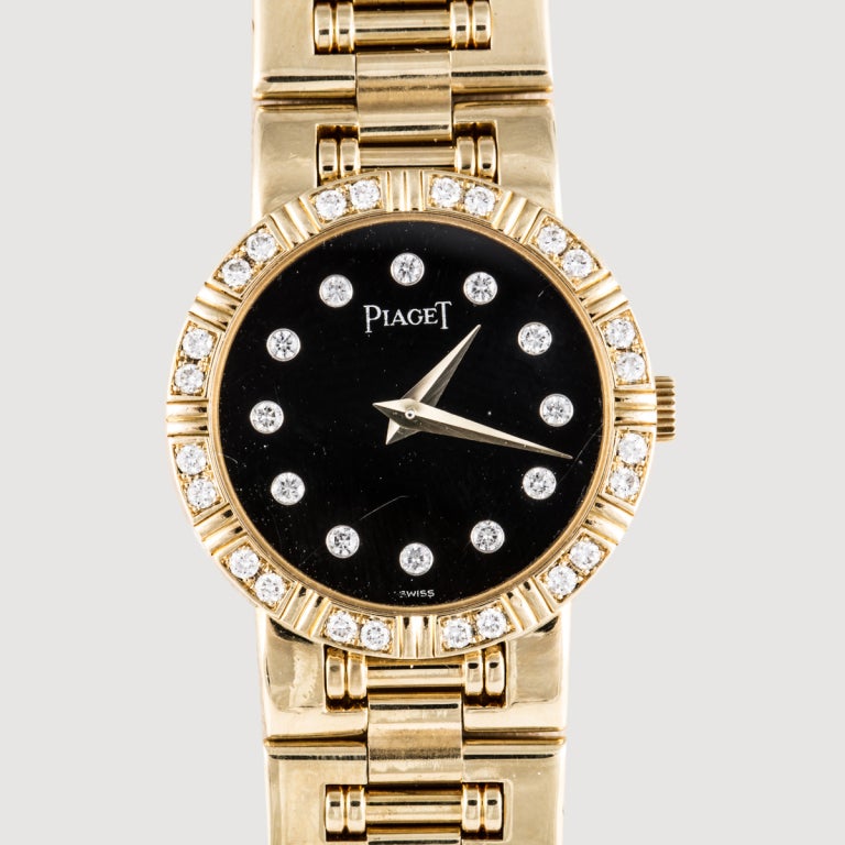 This is an 18k yellow gold lady's Piaget Dancer bracelet watch. It features a black dial with diamond hour-markers, as well as a diamond bezel, all factory-original.
