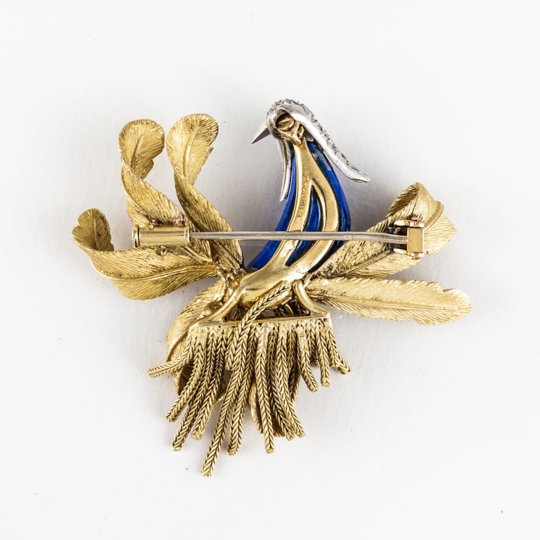 This French 18k yellow gold pin depicts a beautiful bird with a lapis body and diamond-encrusted head. The chains on the bottom of the pin move freely. The total diamond weight is 0.75 carats.