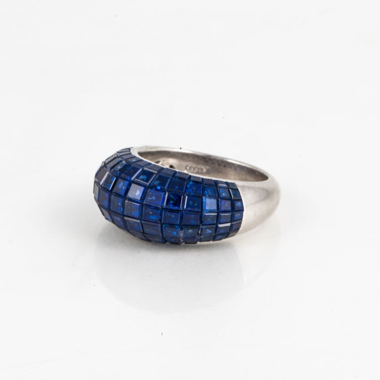 Platinum bombé style ring with 105 invisible-set square blue sapphires that total approximately 6.50 carats. Very clean and tailored ring.  The ring is a size 6 1/4 and may not be sized.  