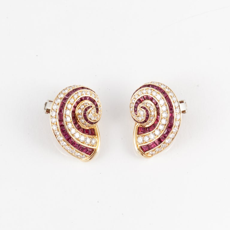 Tiffany & Co. earrings composed of 18K yellow gold with rubies and diamonds depicting a shell.  There are 3.75 carats of round brilliant-cut diamonds, F-G color, and VVS clarity.   There are 100 square-cut rubies.  These earrings are a clip-style