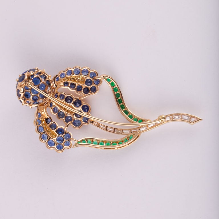 Broche grande fleur d'Oscar Heyman en or jaune 18 carats avec saphirs, émeraudes et diamants.  Il y a 2,07 carats de diamants baguettes, de couleur F-G et de pureté VVS1-VVS2,  42 diamants de couleur jaune fantaisie totalisant 0,50 carats.  En