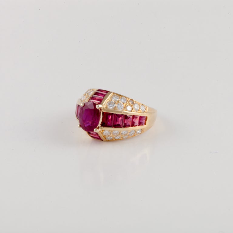 Oscar Heyman ring composed of 18K yellow gold, rubies, and diamonds.  The featured oval shaped ruby is 1.68 carats, and is accented by calibré cut rubies that total 2.41 carats.  Additionally there are 32 round diamonds that total 1.26 carats.  The