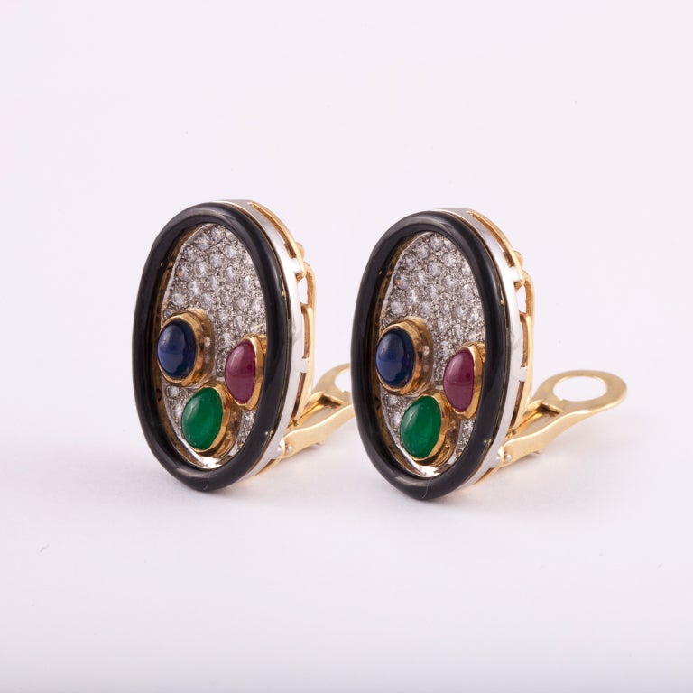 Earrings in an oval shape composed of 18K yellow gold and platinum with a black enamel frame and pavé diamonds with cabochon sapphires, emeralds, and rubies.  The total diamond weight is 3.25 carats.