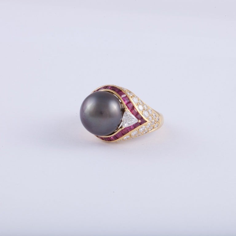 Ring composed of 18K yellow gold featuring a cultured Tahitian pearl accented by diamonds and rubies.  The pearl measures 13.9 mm. rubies total 2.60 carats, and diamonds total 3 carats. The ring is a size 8 3/4.