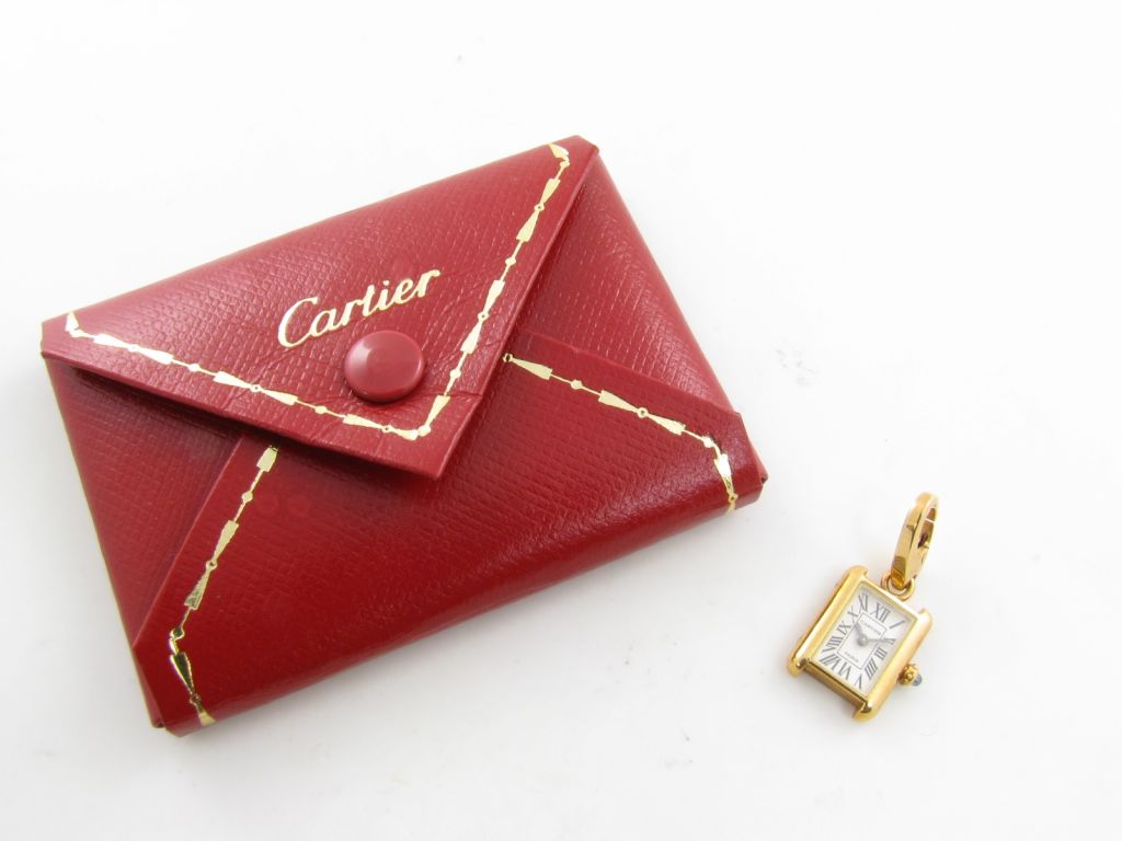 An 18 karat yellow gold charm.  Cartier.  Designed as a replica of a classic Cartier tank watch.  Signed Cartier Made in France serial number 725996.
