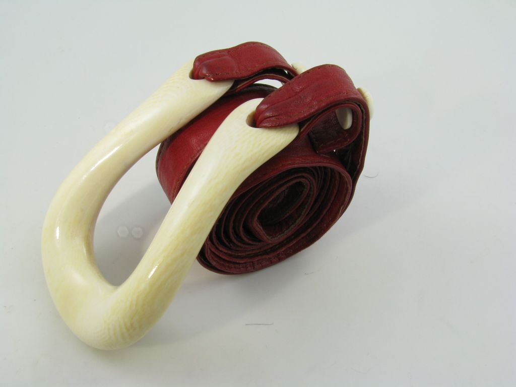 An Ivory and red leather belt by Elsa Peretti Tiffany & Co.  Circa 1970's.  The ivory horseshoe shaped buckle is suspended from a red leather belt with two ivory buttons to hold the belt to the buckle.  The belt and buckle have a total length of 43