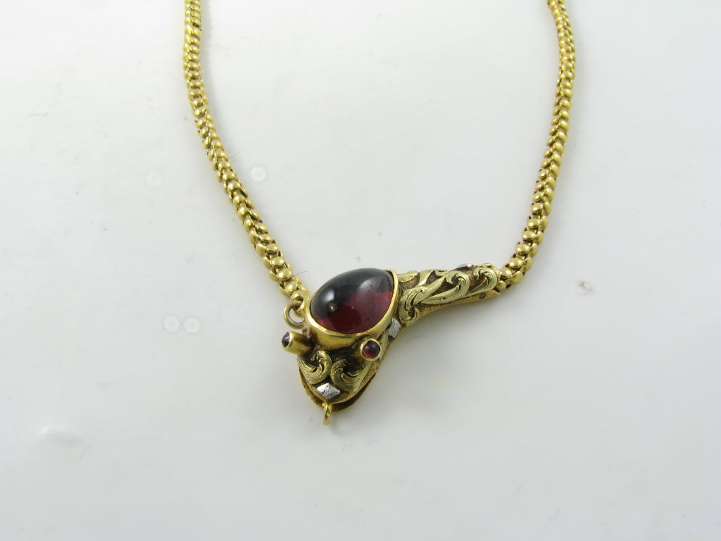 A Victorian 15 karat yellow gold and garnet snake from necklace.  England, circa 1860. The necklace is formed as a snakes body, the snake head clasp is bezel set with a pear shaped foil backed cabochon garnet, the eyes are each set with a cabochon