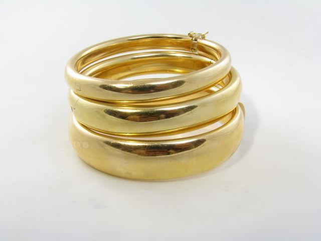 A set of three (3) 18 karat yellow gold hinged bangle bracelets by Wempe.  Circa 1980.  Each signed WEMPE 750.  The three bracelets are of graduated widths measuring 1/4, 1/2 and 5/8 inch wide.  The three bracelets have a gross weight of