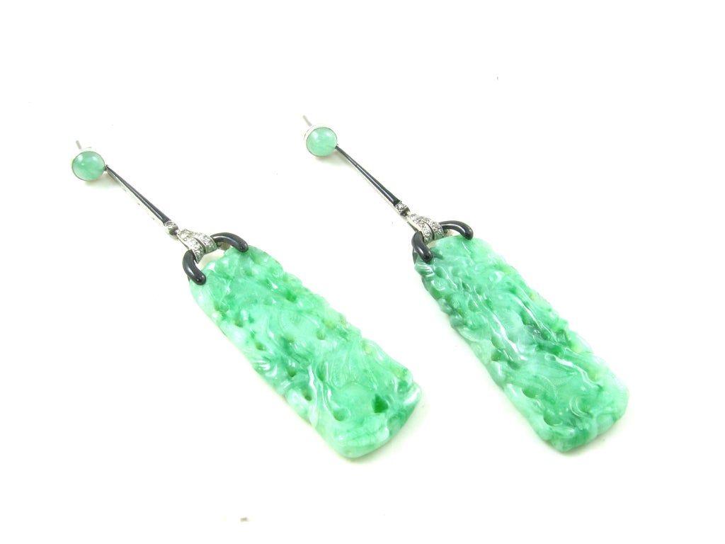A pair of Art Deco platinum, diamond and black enamel mounted natural jadeite earrings with GIA Identification Report 1152585303, dated July 31, 2013.  Circa 1920. The jadeite pendants are of tapered rectangular form, pierced and carved with foliate