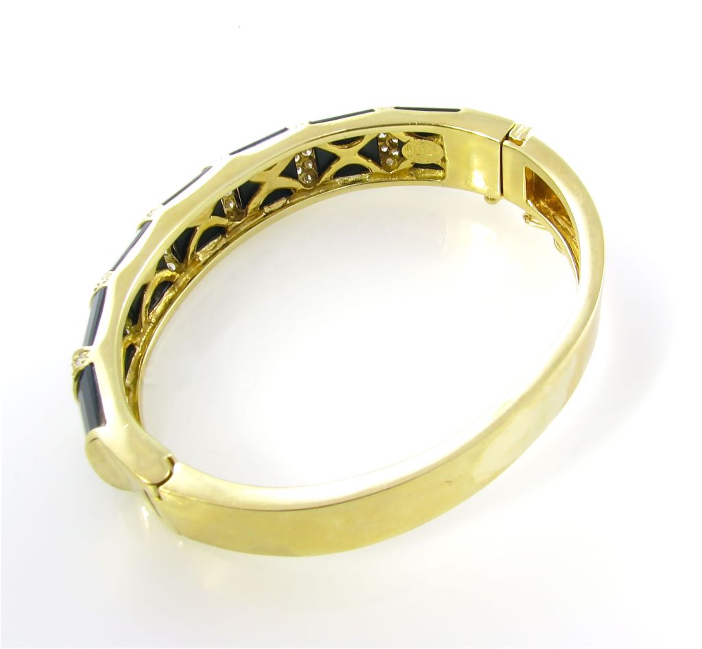 A La Triomphe 18 karat yellow gold, black onyx and diamond hinged bangle bracelet.  Circa 1970â??s.  Signed 18 KT La Triomphe.  The hinged bangle bracelet is set with 7 convex faceted onyx plaques alternating with 6 yellow gold pave diamond navette