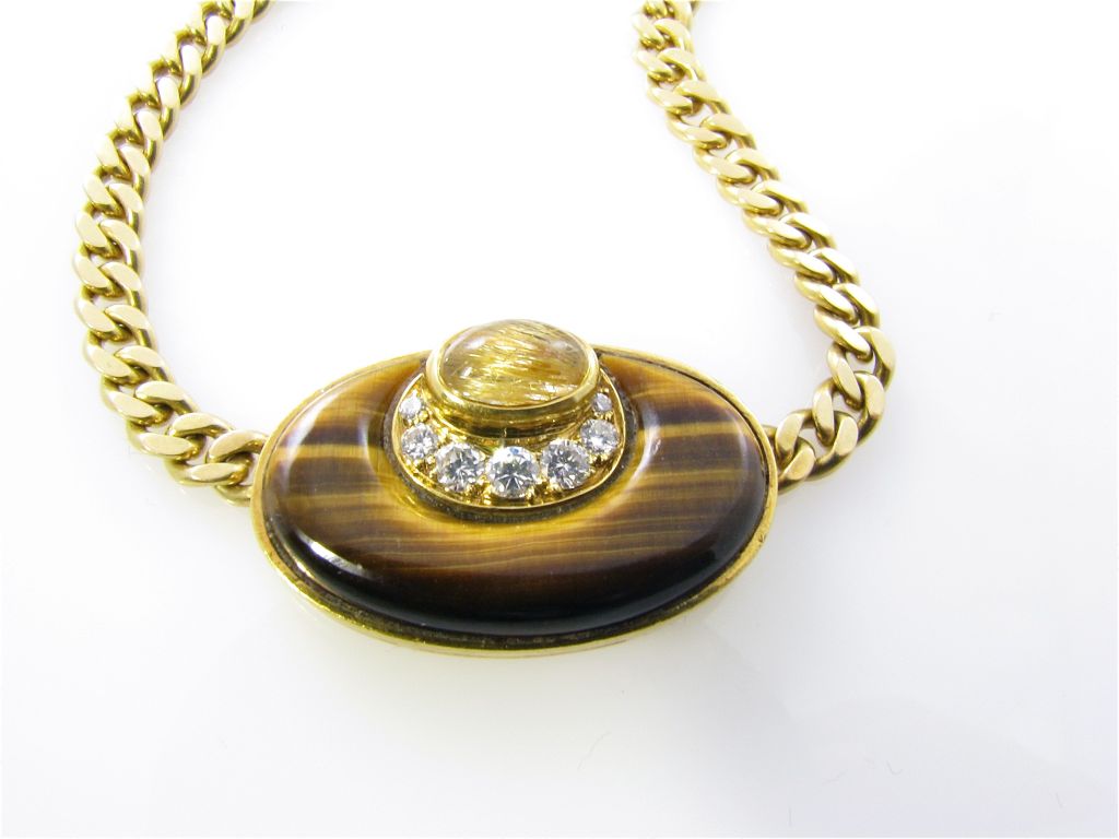 A Bulgari 18 karat yellow gold, tigerâ??s eye and diamond necklace.   Circa 1970.  Signed Bulgari Made in Italy 20 Kt BV3.  The choker length chain link necklace is set with a center oval plaque with 2 concentric cabochon tigers eye stones divided