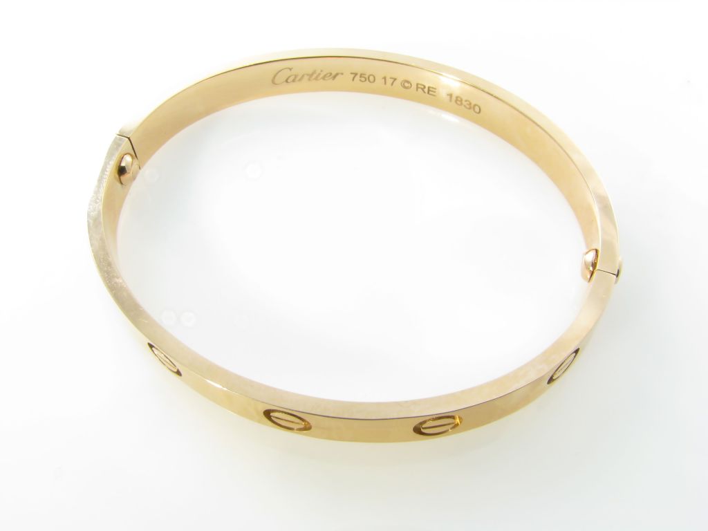 A Cartier 18 karat rose gold “Love” bangle bracelet.  Signed Cartier 750 17 © RE 1830.  The rose gold bangle bracelet has 2 screws, one on each side.  The bracelet has a gross weight of approximately 34.5 grams and is a size 17.