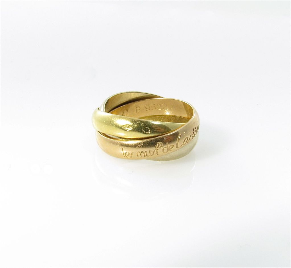 A Must de Cartier 18 karat tri-color gold â??Trinityâ?? ring.  Circa 2005.  Signed Les Must de Cartier 750 47 P9620A and hallmarked with French maker and gold marks.  The ring is a size 47 (US size 4).  The ring has a gross weight of approximately