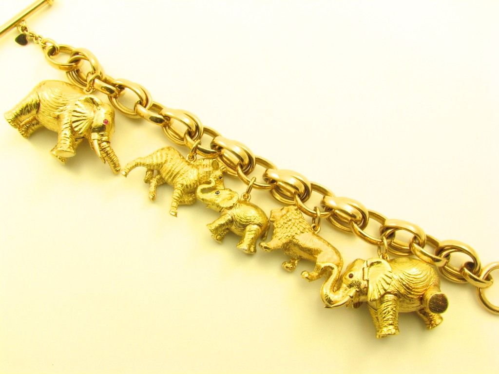 An 18 karat yellow gold charm bracelet.  Bielka.  The bracelet is composed of (3) three elephants, a zebra and a lion set with ruby and sapphire eyes.  Gross weight approximately 210 grams.