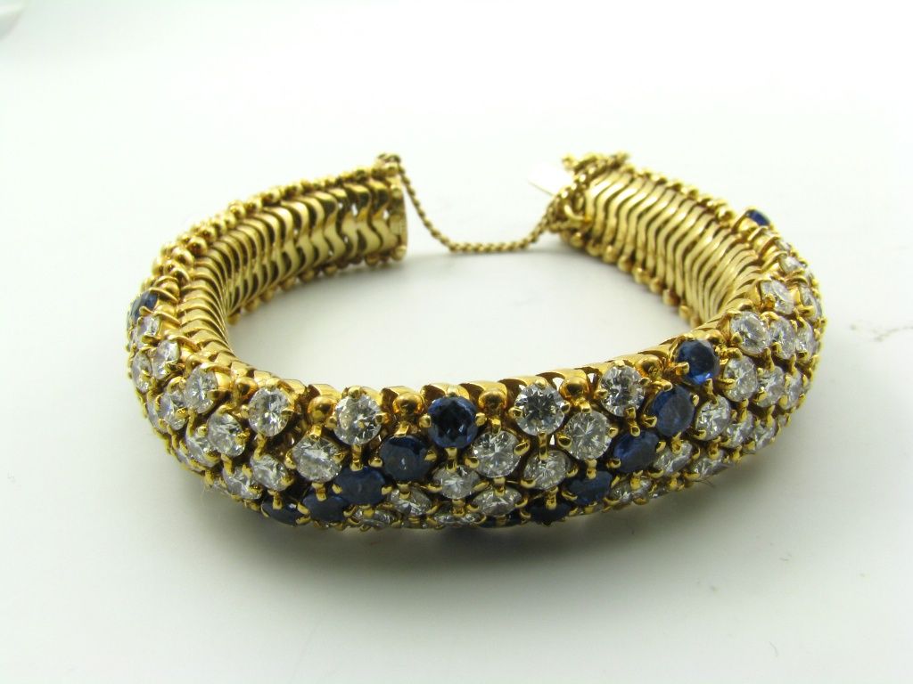 An 18 karat yellow gold, sapphire and diamond bracelet. Stamped Italy. The cous cous style bracelet centers twelve rows of diamonds accented by four rows of sapphires. The bracelet is set with (84) diamonds weighing a total of 9.50 carats and (28)