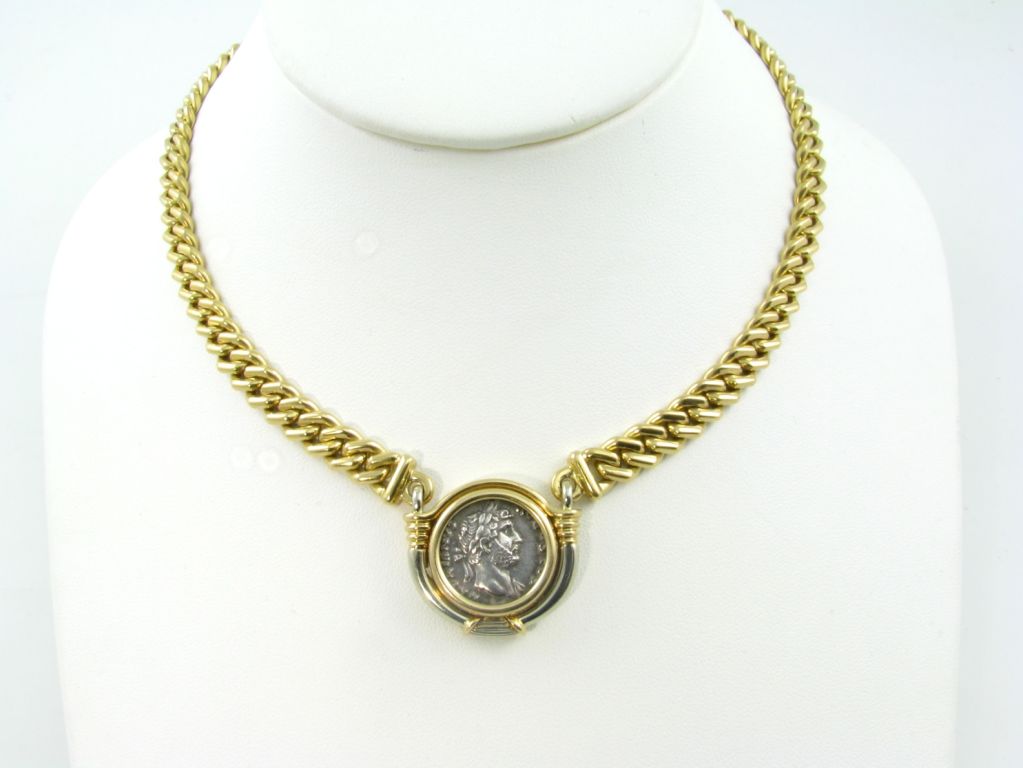 An 18 karat yellow gold and coin necklace.  Signed Bulgari.  The solid link chain centers an antique coin set in a bezel that is engraved on the back Roma Hadrianus, 117-138.  Approximate weight of necklace is 74.8 grams.