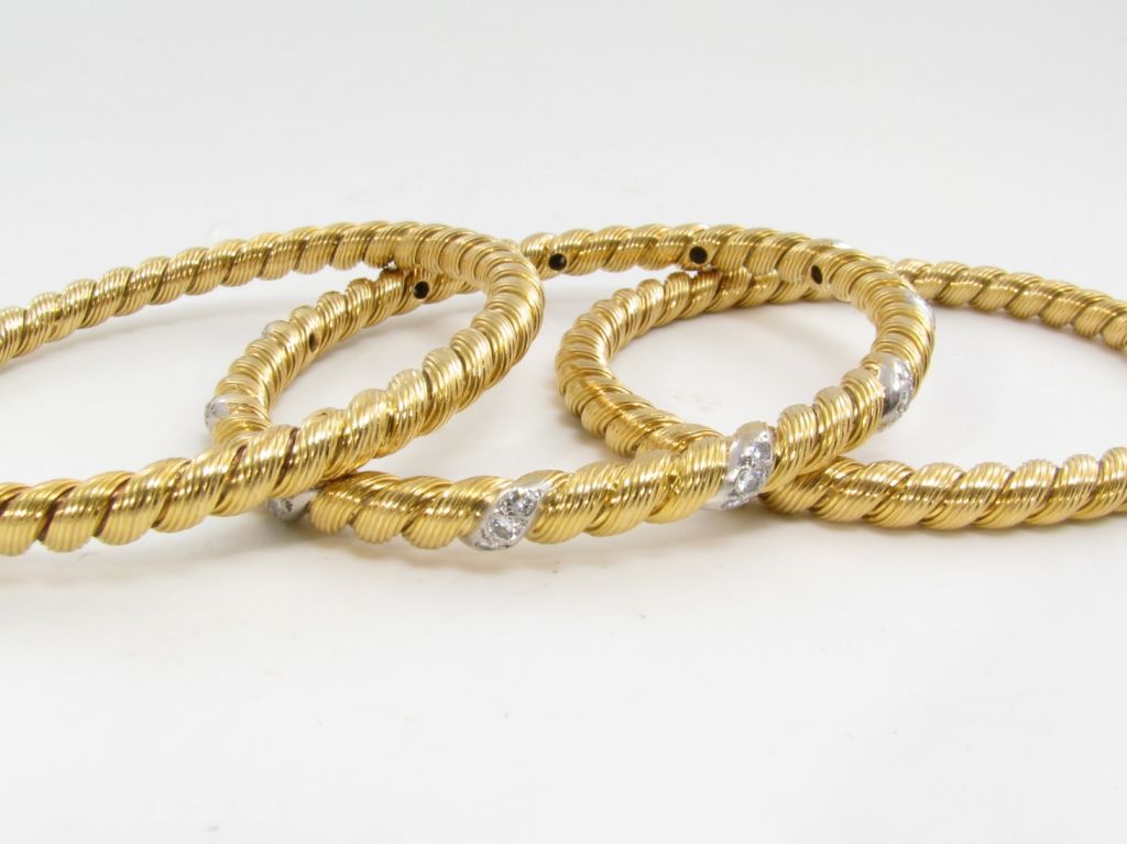 A set of (3) three 18 karat yellow gold and diamond bangle bracelets.  Signed Van Cleef and Arpels, France.  One bangle bracelet has (33) thirty three round diamonds approximate weight 1.10 carats.  The other two bangles are all gold.   Approximate