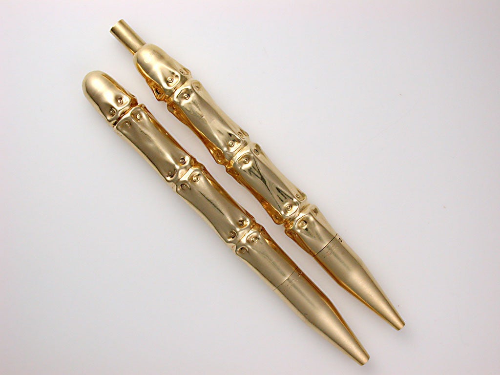 Stylish and heavy in the hand, the ball point pen clicks to open with a sprung thumb piece, the lead pencil twists to open, designed to imitate bamboo, signed Cartier in script, stamped 14K, numbered, with maker's mark for Louis Tamis, circa 1945.