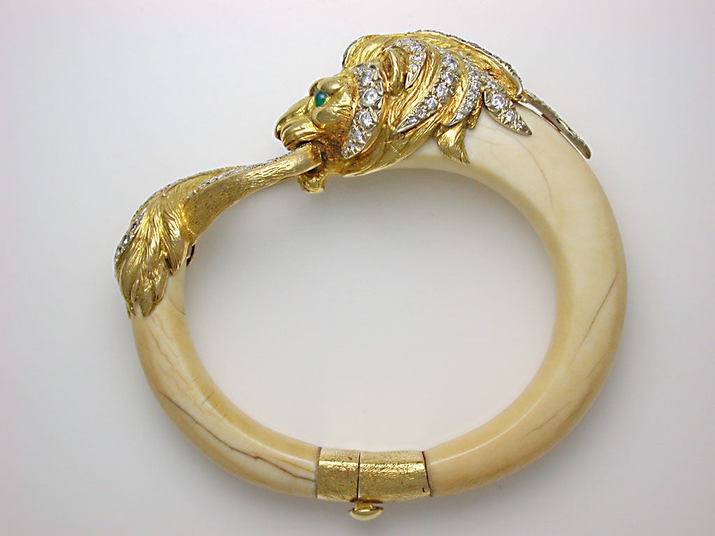 The stylish cuff bangle designed as a male lion, his body carved from two tapering arcs of ivory, sweeping around to bite his looped tail, secure clasp and safety catch at base, beautifully accented with 3 carats of white diamonds and green onyx