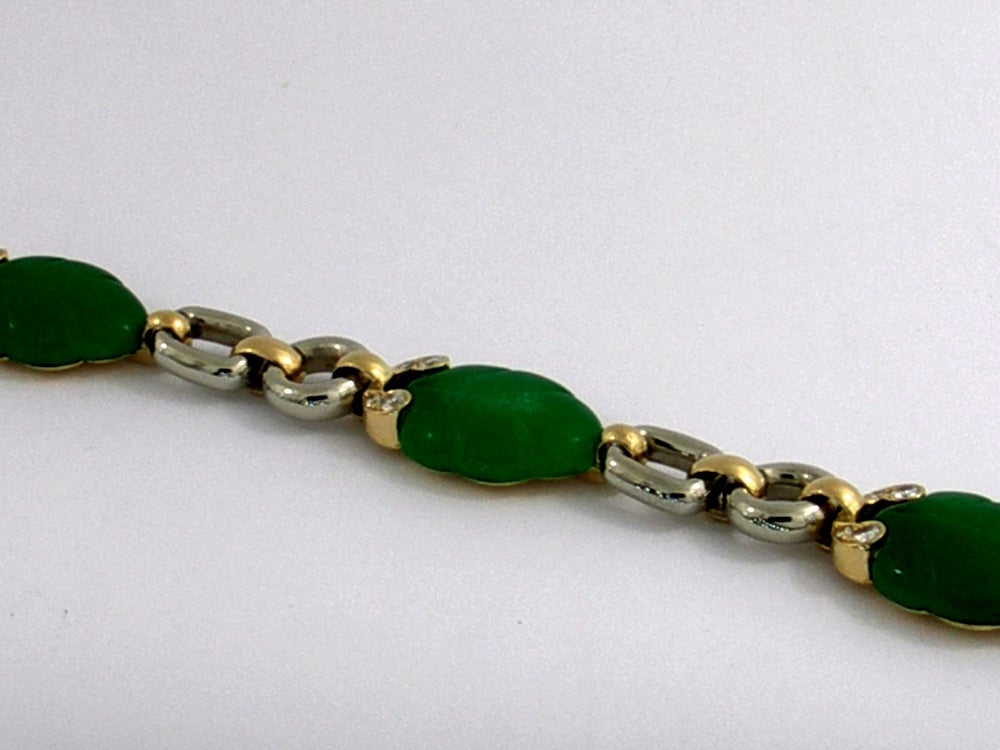 This sleek bracelet by Cartier features Chrysoprase Chalcedony for it's jade-like green color. Each piece is beautifully carved into a leaf which is then incorporated into it's 18K gold links. At the base of each leaf, are four round brilliant cut