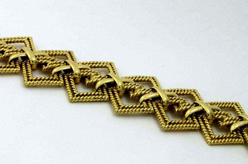 One ladies 18K yellow gold bracelet comprised of interwoven diamond shaped links measuring a total of 1 3/4 inches wide, with high polished X motif embellishments in the center. Signed Tiffany & Co.