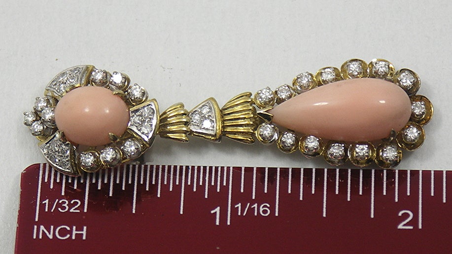 Part of a three piece suite, these lovely earrings are fashioned from 14K Yellow Gold, and are set with two oval shaped and two pear shaped angel skin coral cabochons. The 82 full cut and single cut diamonds weigh an approximate total of 2.00CT of