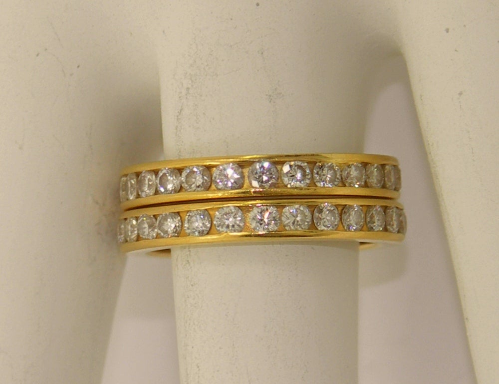 One pair of 18K yellow gold, channel set eternity bands by Tiffany and Co. Each band is set with approximately 1ct of overall F color and VVS2/VS1 clarity, round brilliant cut diamonds. The bands are a size 6, and would compliment item #