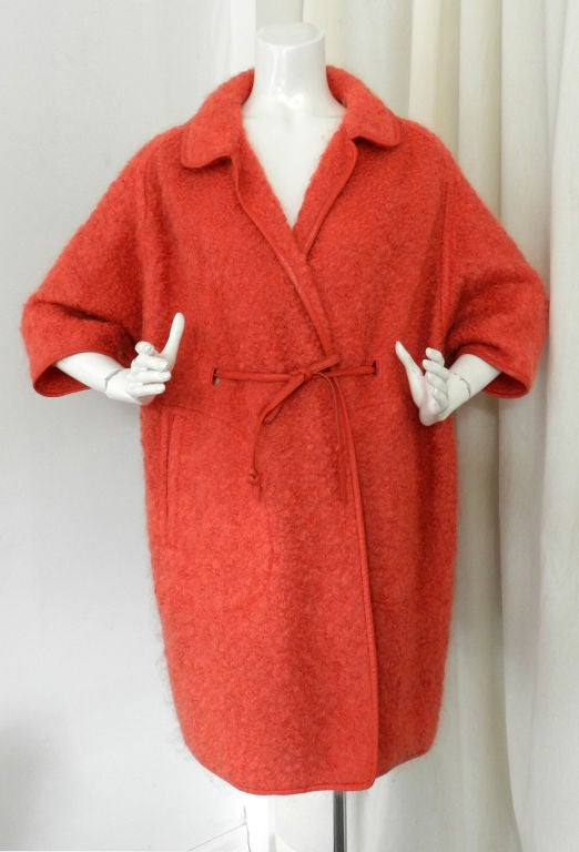 Vintage 1960's Bonnie Cashin for Sills salmon coloured boucle coat. Material is textured boucle wool/mohair and trimmed with leather.  Unlined. The coat has 3/4 length batwing sleeves, side hip pockets, and waist ties with leather cord belt.