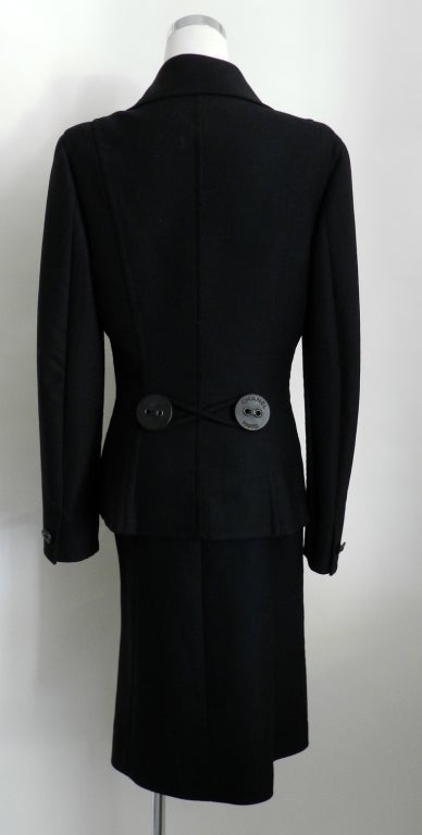 Chanel 2002 Fall/Winter black wool suit with large logo leather buttons.  Excellent previously owned condition. Jacket is unlined double face wool.  Skirt and jacket are tagged size 40 but fits like a 36 so please check measurements. Skirt waist is
