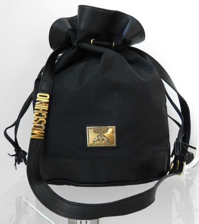 Vintage early 1990's Moschino by Redwall black nylon and leather trim purse. Drawstring bucket bag with long leather cross-body strap. Body measures 13 x 10.5 x 6 inches and strap has a maximum drop of 17.5