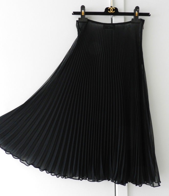 Chanel resort 2002 collection sheer black pleated midi column skirt. Side zipper and black metal jeweled CC logo at left hip. Excellent previously owned condition. Tagged size Chanel 38 but maximum waist measurement of 25