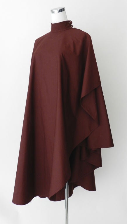 Jean Louis Scherrer burgundy cotton cape in lightweight cotton for Spring.  Wrap style design that fastens with 4 buttons at neck and shoulder. Graduated hemline creating layered effect.  Slit on right side to allow arm to come through.  Free size