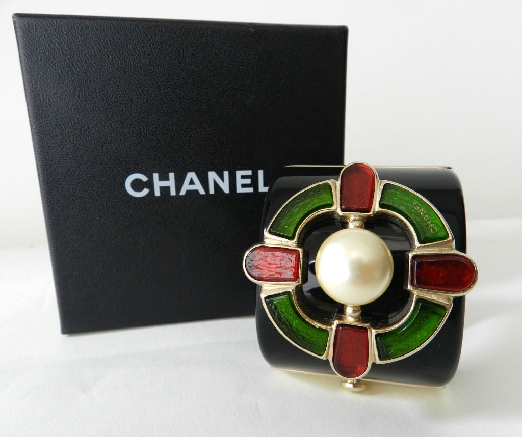 Chanel Gripoix glass Monte Carlo cuff bracelet.  Black lucite with red and green glass and centre faux pearl.  Perfect unworn condition with original store sticker inside.  Measures 2 inches wide and 6.75 inches interior circumference.

Shipping