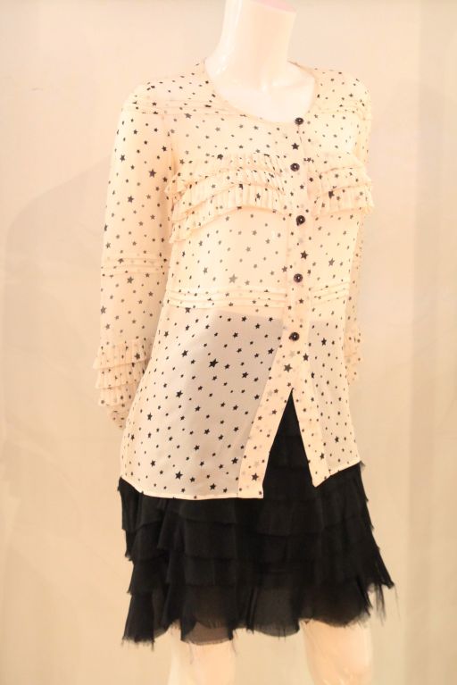 This CHANEL 03A Ivory/Blue Navy Stars Silk Sheer Blouse w/ Pleated Trim evokes the timeless and classic design of Chanel. As part of Chanel's 2003 Autumn Collection, this blouse is a must-have.<br />
<br />
The blouse closes with five front button