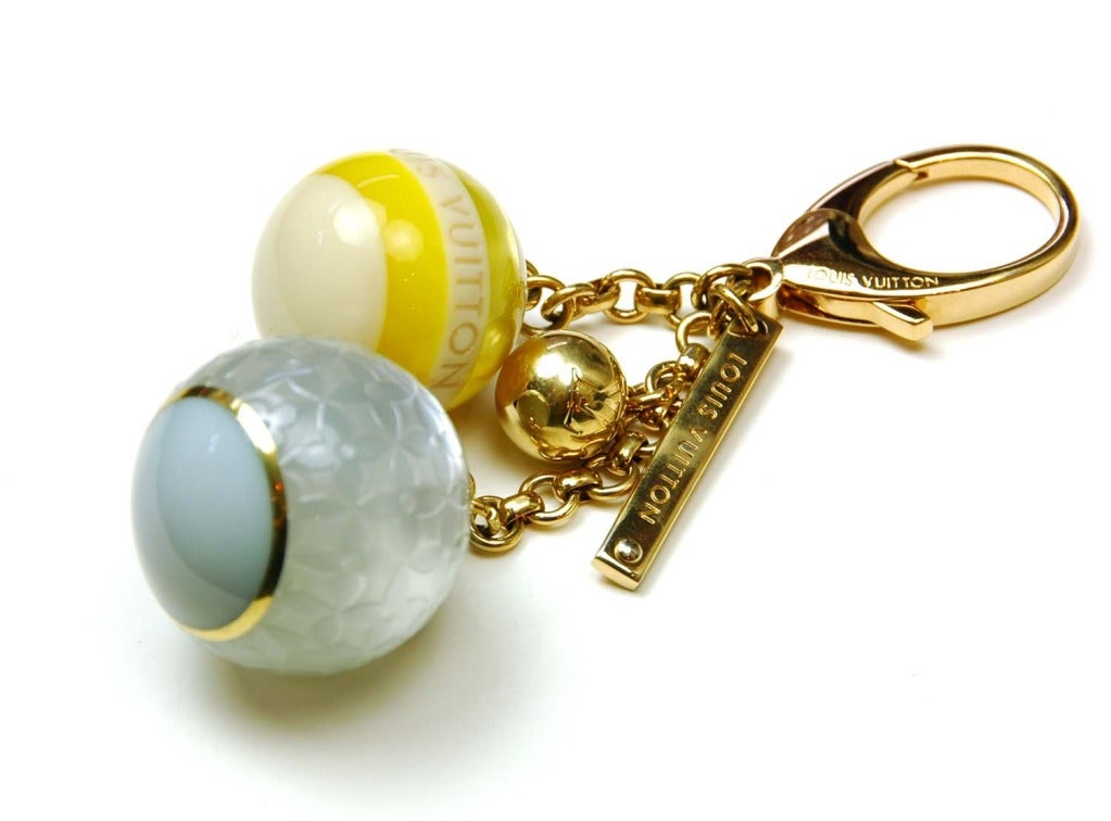 LOUIS VUITTON Gold, Yellow & Blue Logo Ball Bag Charm/Key Chain
Features gold hardware, oversize lobster clasp, dangling gold bar stamped LOUIS VUITTON, one small gold logo ball, one medium yellow and white ball with LOUIS VUITTON engraved, one