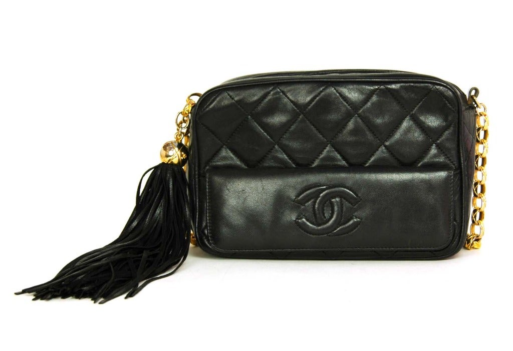 CHANEL Black Quilted Camera Bag W. Tassel c. 1990

    Age: c. 1990
    Made in Italy
    Materials: black lambskin leather, gold hardware, black tassel.
    Features miniature camera bag shape with top zipper (has attached gold CC ball charm