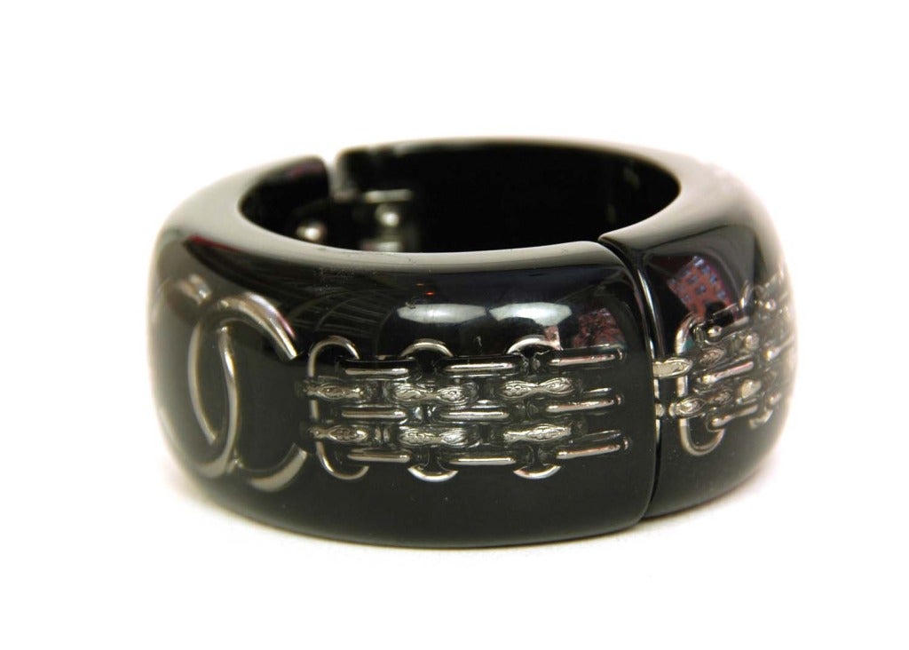 CHANEL Thick Black Resin Clamper Bangle Bracelet W. Embedded Chain & CC c. 2011 RT. $1185
    
Age: c. 2011
Made In France
Materials: Black resin, silver CC, silver bijoux chain.
Black resin bangle with floating silver bijoux chain and CC