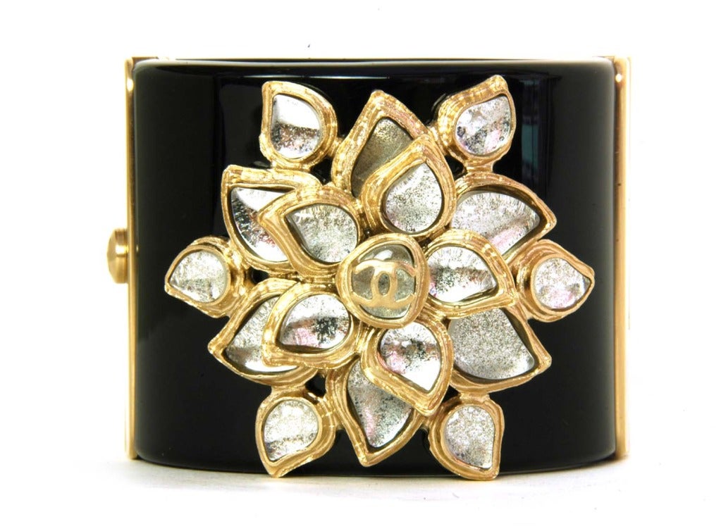 CHANEL Black Resin Clamper Cuff W. Crystal Flower Paris Bombay Collection c. 2012

Age: c. 2012
Made In Italy
Materials: black resin, crystal and silver flower, small silver CC charm.
Thick black resin bangle with layered crystal flower with
