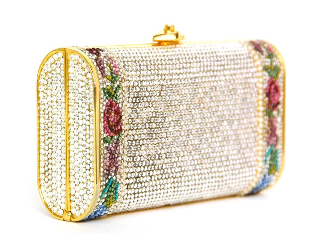 JUDITH LEIBER Minaudiere Crystal Clutch W. Flowers, Pearls & Gold Shoulder Strap

Materials: multicolor crystals, faux pearls, goldtone metal, pebbled gold leather lining.
Features rectangular minaudiere clutch with crystallized body with gold