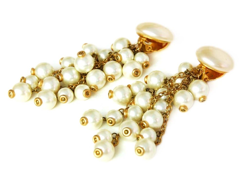 CHANEL Cascading Faux Pearl And Gold Dangling Earrings c. 1988

Age: c. 1988
Made in France
Materials: faux pearls, goldtone metal.
Features oversized faux pearl with three different length strands of gold links and cascading pearls. 
Stamped