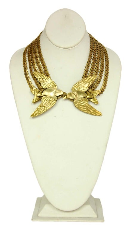 CHANEL Brass Tone 5 Strand Link Necklace W. Two Kissing Birds 1982

Age: 1982
Materials: brass tone links, brass tone birds, brass chain adjuster.
Features 5 strands of hammered and smooth links with two large kissing birds in the front and a