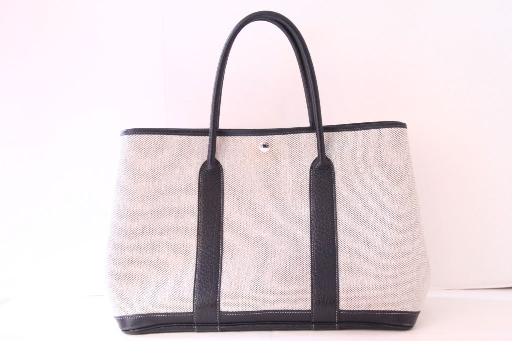 A perfect everyday bag for everyone!<br />
<br />
Hermes Garden Party tote in toile with black leather trim and double black rolled leather top handles.  It closes with a snap button closure at opening.  The sides are expandable with snap button