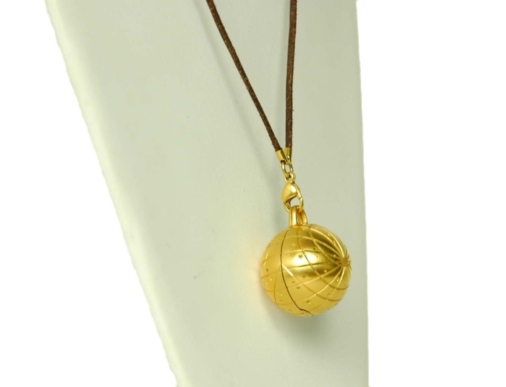 HERMES Gold Globe Necklace With Stars On Brown Leather Chain
Materials: goldtone metal, waxed leather cord.
Features gold globe with concentric circles and stars. Globe opens when cord is detached via lobster clasp (it is hollow inside).
Stamped