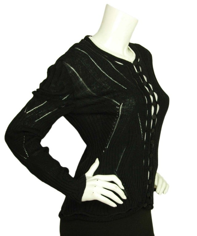 CHANEL Black Cardigan Sweater W. Ribbed & Cutout Details Sz. 10
Materials: Rayon blend.
Features crew neck cardigan with ribbed, crochet and cutout design. Logo buttons down center. 

Size tag is missing.
Estimated to fit a US size