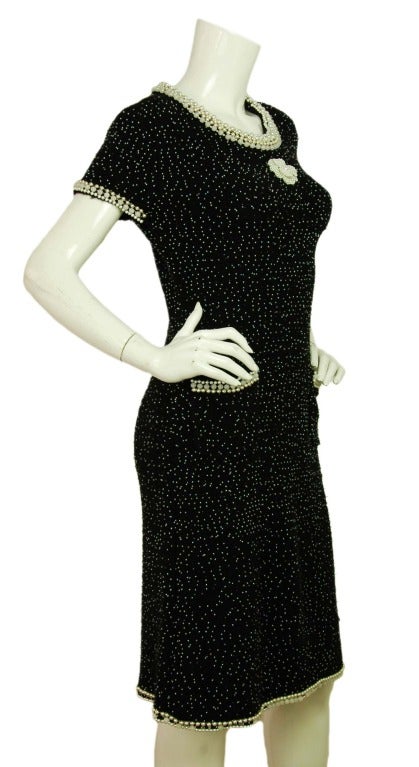 Chanel Black Shortsleeve Dress W/Pearl Beading And Camelia - Sz 4

Age: c. 2005
Made in Italy
Composition: 45% cashmere, 30% wool, 15% cotton, 10% nylon
Two front pockets
Small pearl beading throughout dress with larger pearls at trim of