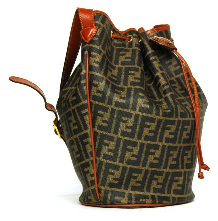 FENDI Brown & Black Monogram Zucca Canvas Drawstring Bucket Bag
Made in Italy
Materials: coated canvas, leather.
Features brown and black monogram zucca print bucket bag. Gathered drawstring top with monogram leather medallion. Leather piping and
