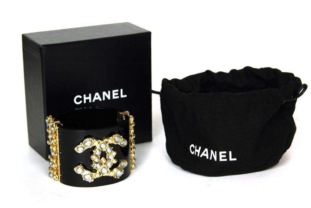 CHANEL Black Resin Clamper Cuff With Poured Glass Stones RT. $2060 c. 2012
Age: 2012
Made in France
Materials: black resin, brushed gold, gripoix (poured glass.)
Features black resin clamper cuff with brushed gold CC with poured glass stones.