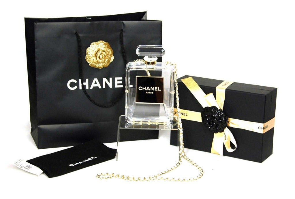 CHANEL Clear Plexiglass 'No. 5' Perfume Bottle Clutch W. Chain Strap c. 2014

Age: 2014
Made in Italy
Materials: clear plexiglass, white leather, goldtone chain links.
Features clear plexiglass perfume bottle frame in the style of Chanel No. 5.