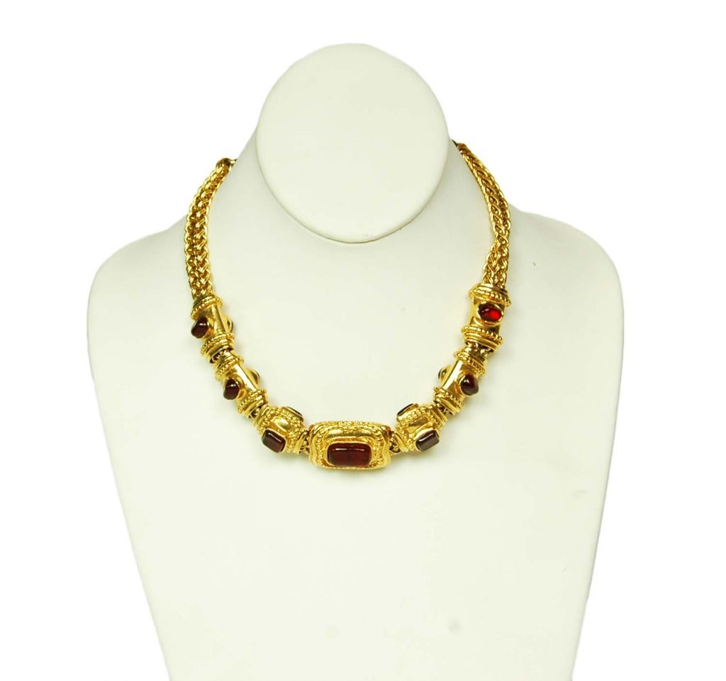 CHANEL Goldtone Choker Necklace W. Red Gripoix Medallions c. 1996
Age: 1996
Made in France
Materials: goldtone metal, red poured glass (gripoix) beads.
Features braided, double strand gold choker with sliding gold and red gripoix medallions.