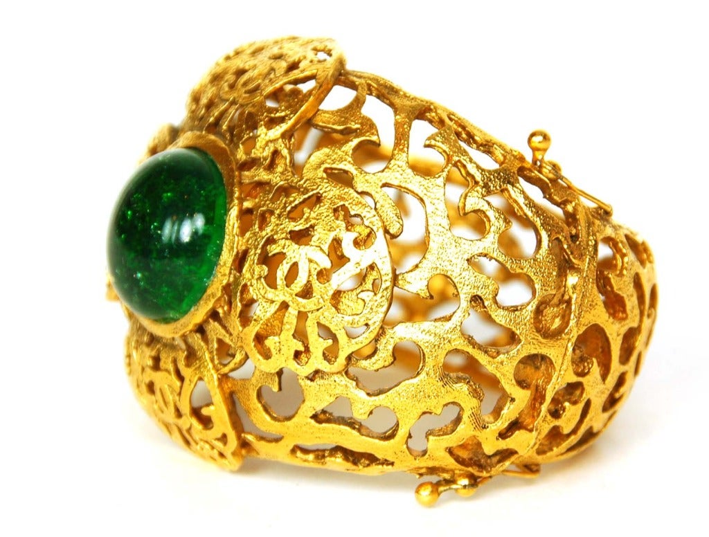 Chanel Vintage '87 Filagre Green Gripoix Cuff
​Features clover shape overlay with cutouts and CC logos
Made in: France
Year of Production: 1987
Color: Goldtone and emerald green
Materials: Metal and poured glass
Closure/Opening: Spring closure